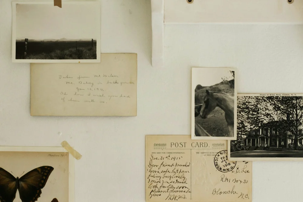 Cartes postales manuscrites et photographies anciennes fixées sur un mur clair