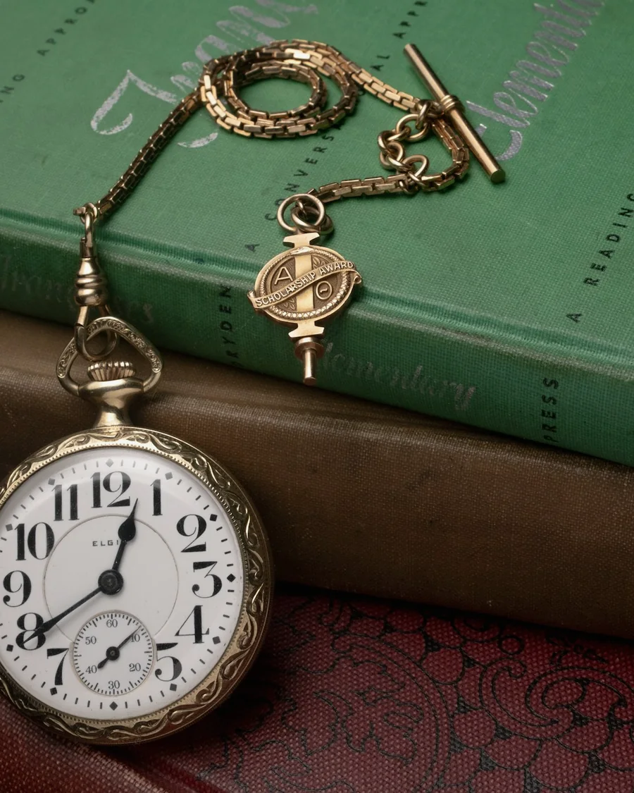 Montre à gousset ancienne posée sur une pile de livres reliés